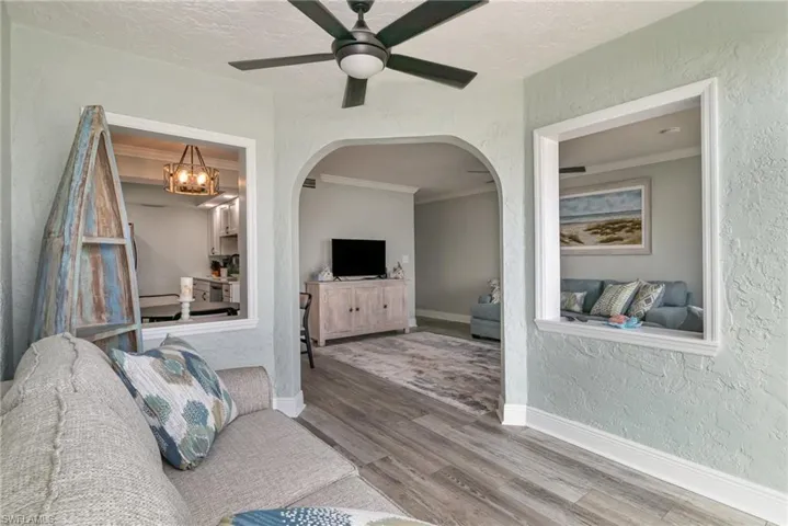 Living area featuring wood finished floors, arched walkways, and a textured wall