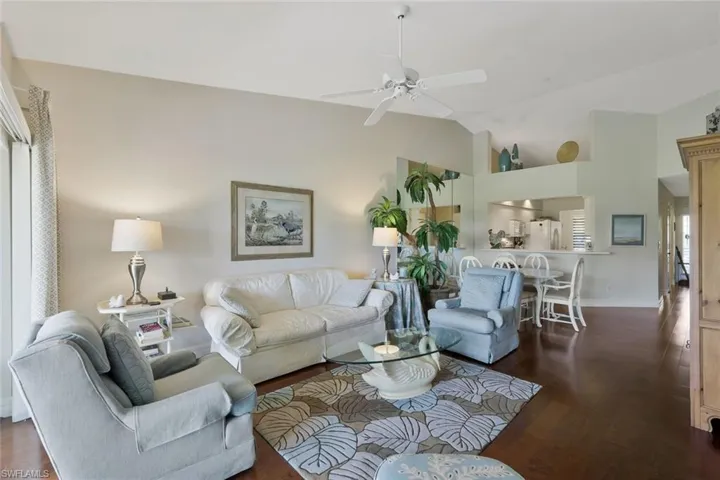 Living area featuring lofted ceiling, dark wood-type flooring, and a ceiling fan