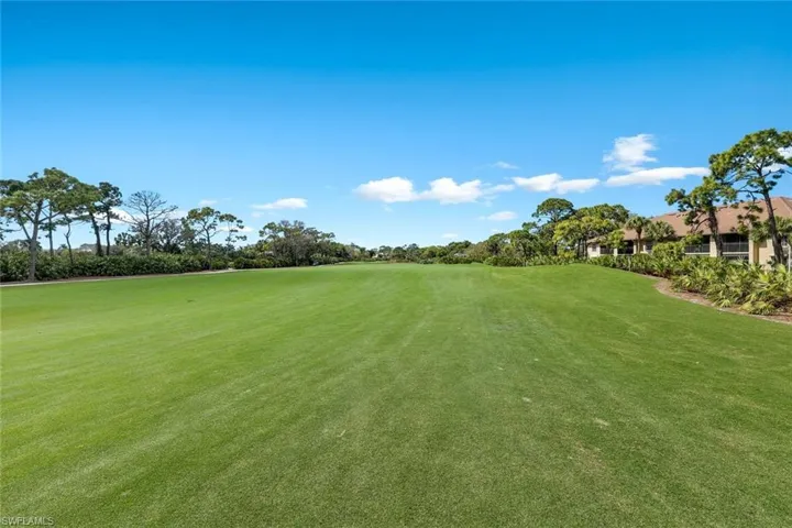 View of grassy yard featuring view of golf course and view of scattered trees