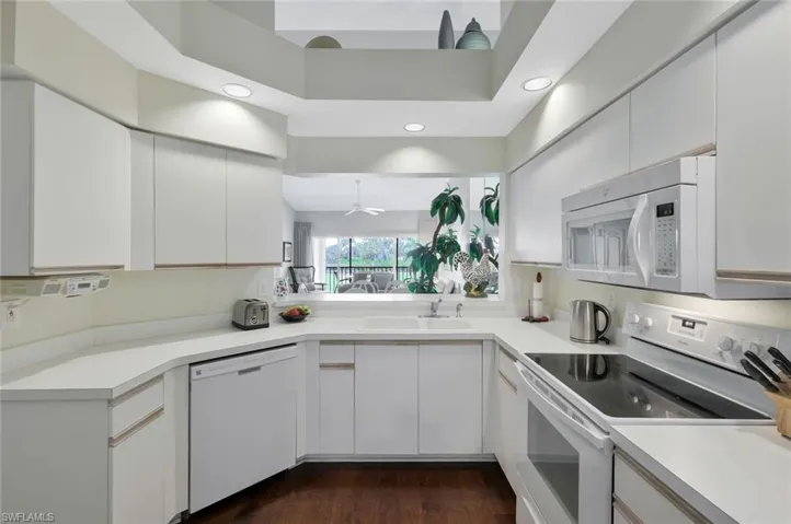 Kitchen featuring white appliances, light countertops, white cabinetry, and recessed lighting