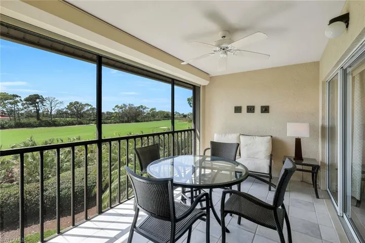 Sunroom / solarium featuring ceiling fan, view of golf course, outdoor dining area, and a balcony