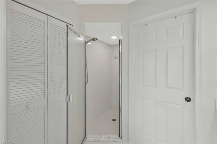 Bathroom featuring a closet and a shower stall