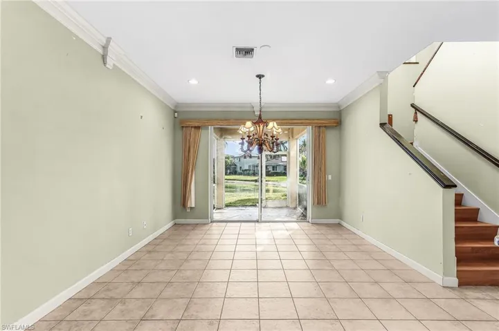 Unfurnished dining area with hanging lights, crown molding, and light tile patterned floors