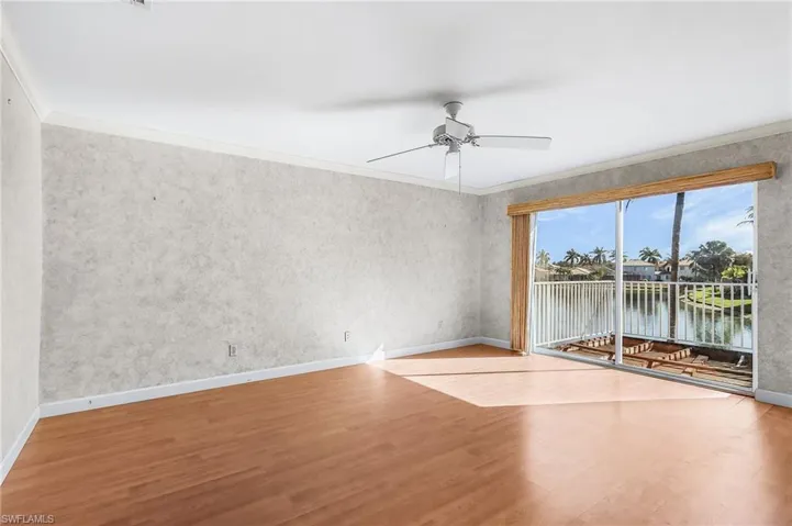 Empty room featuring wood finished floors, crown molding, a ceiling fan, and a water view