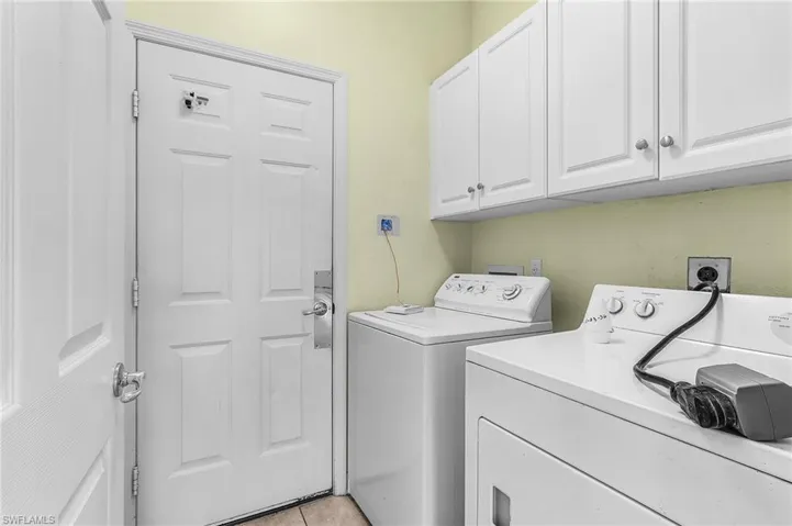 Laundry room featuring washer and dryer, cabinet space, and light tile patterned floors