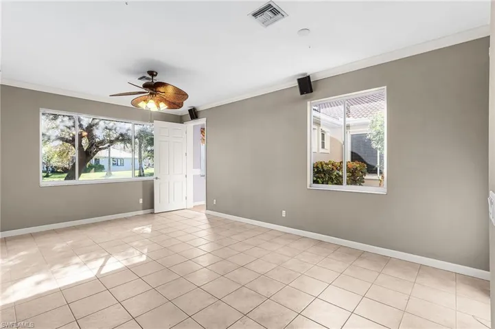 Spare room featuring a ceiling fan, crown molding, and light tile patterned flooring