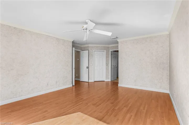 Unfurnished room featuring ornamental molding, light wood-style flooring, and ceiling fan