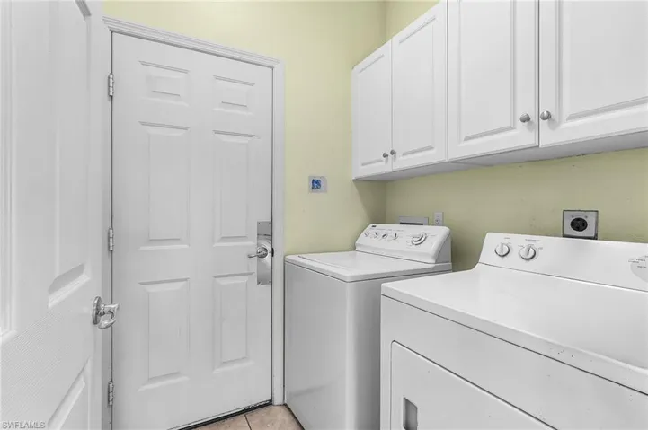 Laundry room with cabinet space, washing machine and clothes dryer, and light tile patterned floors