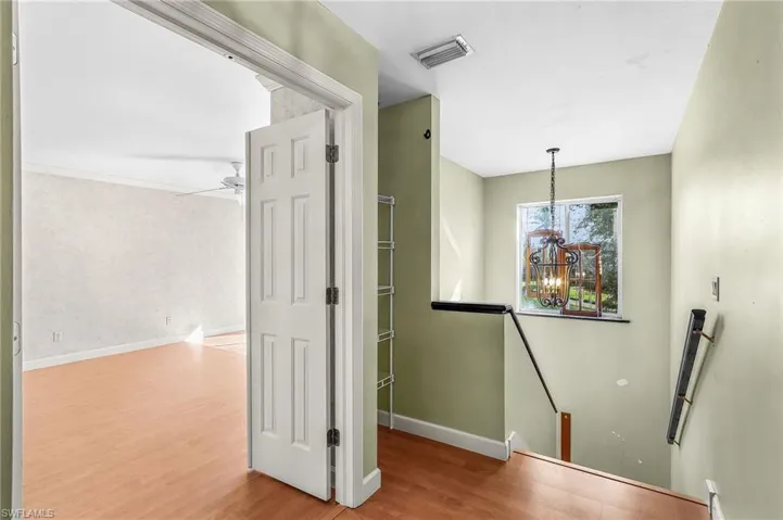Hallway featuring an upstairs landing, light wood-type flooring, and suspended lighting