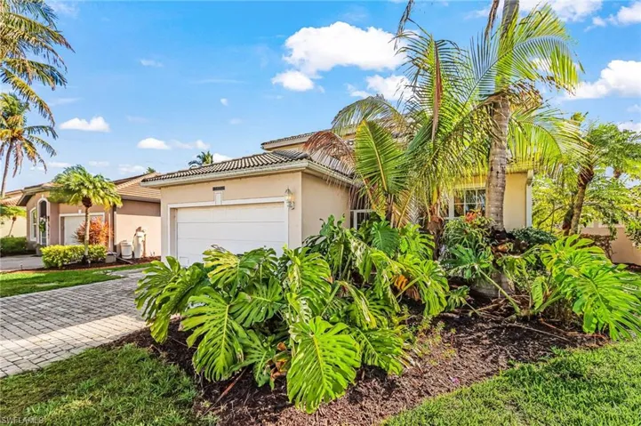 View of front of property featuring stucco siding, driveway, a tiled roof, and a garage