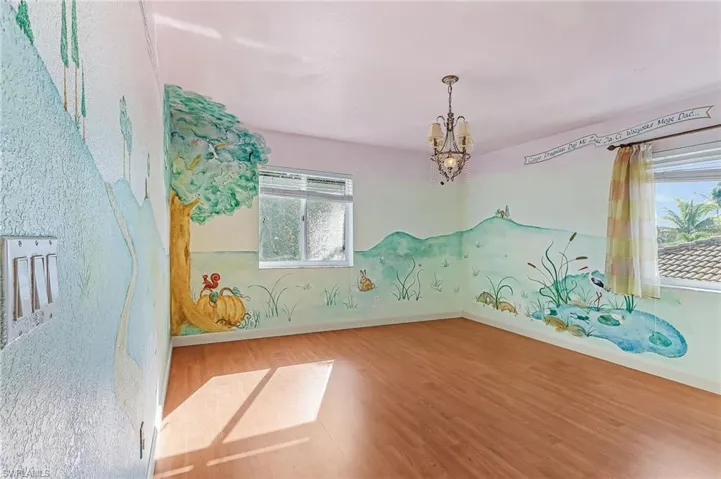 Spare room featuring hanging lights and wood finished floors