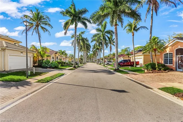 View of asphalt street featuring a residential view, sidewalks, street lights, and curbs