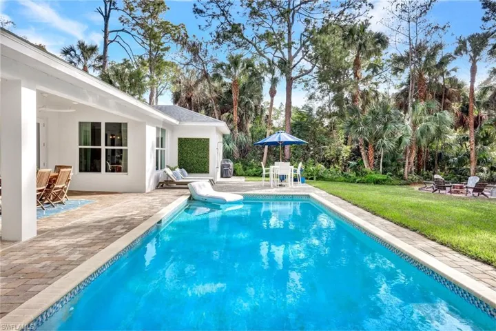Outdoor pool featuring a patio area, an outdoor fire pit, a yard, and outdoor dining space