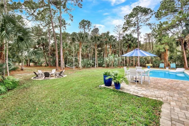 View of grassy yard featuring a patio, an outdoor pool, and an outdoor fire pit