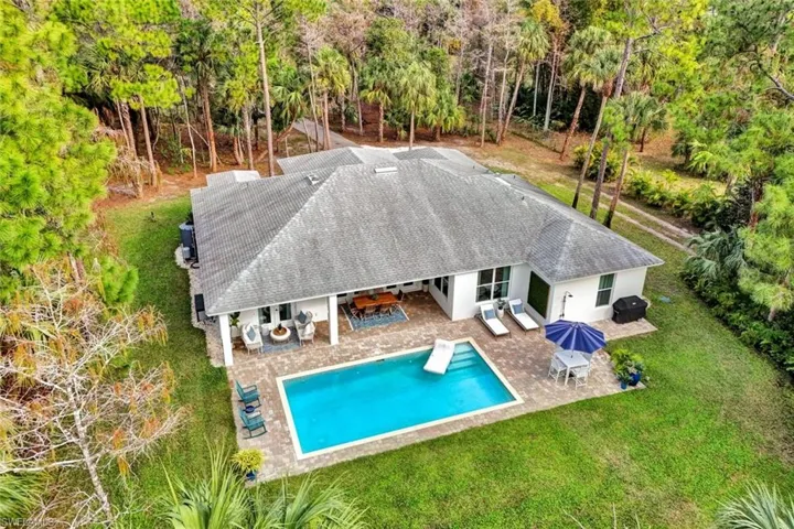 Back of property featuring stucco siding, a shingled roof, a patio area, outdoor dining area, and a lawn