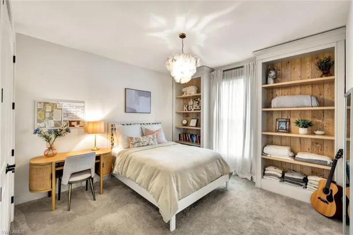 Carpeted bedroom featuring a chandelier and an office area