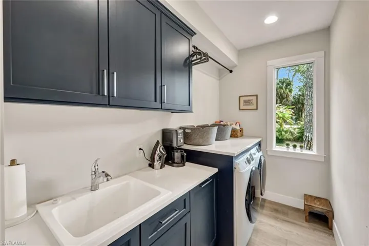 Washroom featuring separate washer and dryer, light wood-style flooring, cabinet space, and recessed lighting