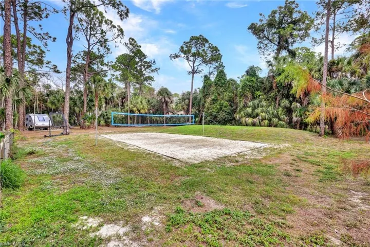 View of home's community with volleyball court and a lawn