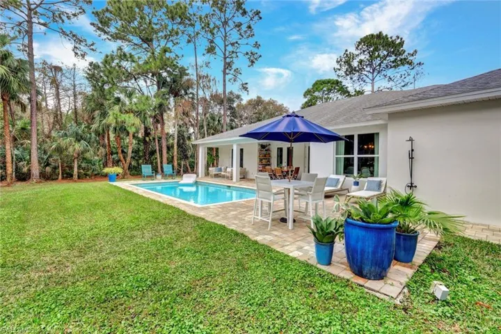 Outdoor pool with a patio area, a yard, and outdoor dining space