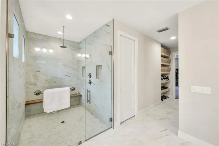 Bathroom with a spacious closet, recessed lighting, light marble finish floors, and a marble finish shower