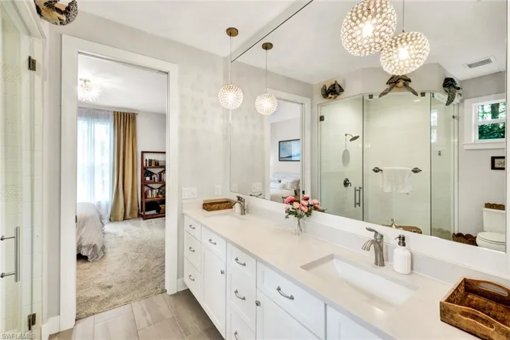 Ensuite bathroom featuring double vanity, a stall shower, and light carpet
