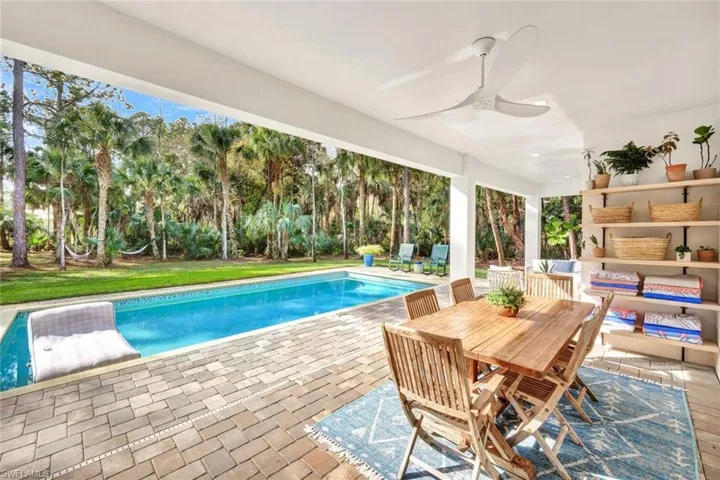 Swimming pool featuring a patio area, outdoor dining area, and a lawn