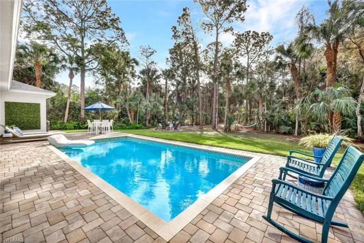 Outdoor pool featuring a patio, a yard, view of wooded area, and outdoor dining area