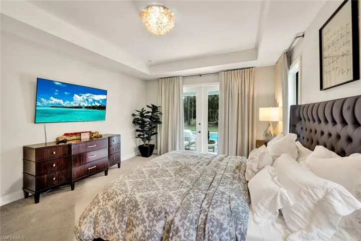 Bedroom with french doors, access to exterior, light colored carpet, and a raised ceiling