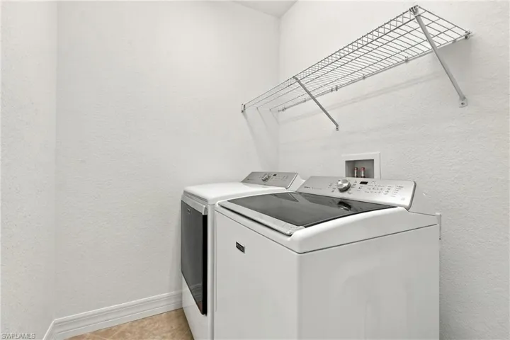 Laundry area featuring neutral wall finishes, tile flooring, and a wall-mounted wire shelving unit