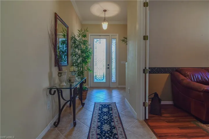 Entryway featuring Diagonally Laid Tile, ornamental moulding, pendant lamp