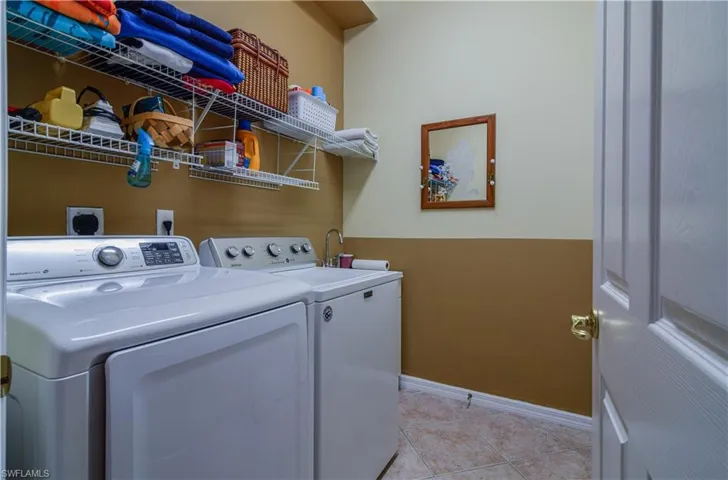 Clothes washing area with washing machine and clothes dryer and light tile patterned floors