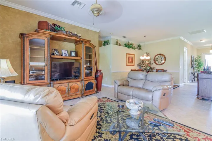 Living room featuring light tile patterned floors, crown molding, and ceiling fan