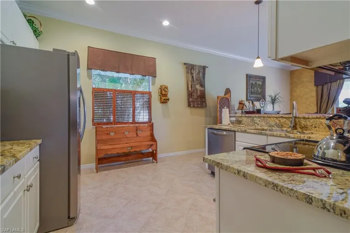 Kitchen featuring white raised panel cabinetry, tasteful backsplash, eclectic brown and gold granite, and stainless steel appliances