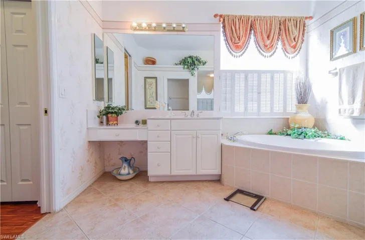 Bathroom featuring tiled tub, wood-type flooring, and vanity