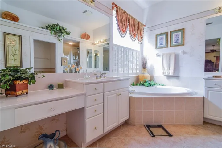 Bathroom featuring a relaxing tiled tub, tile patterned flooring, and vanity