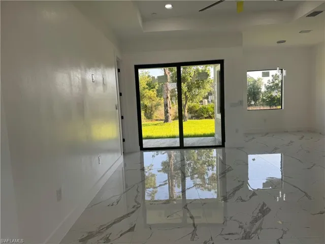 Tiled empty room featuring a raised ceiling