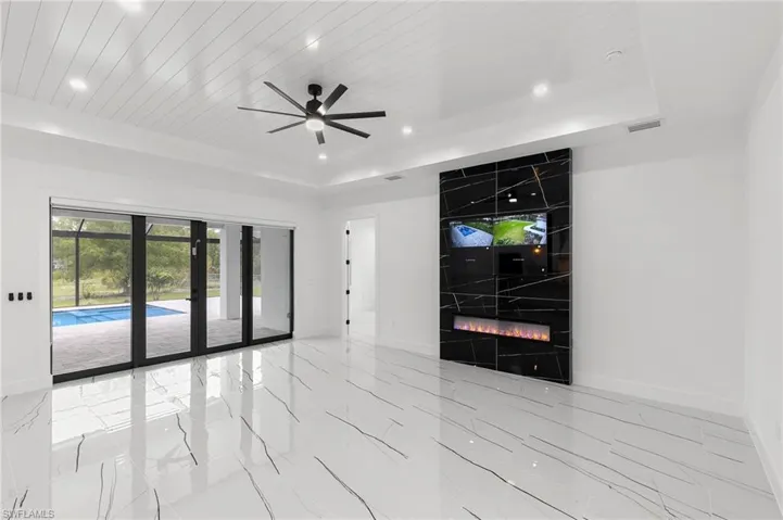 Unfurnished living room featuring ceiling fan, a fireplace, a raised ceiling, and wood ceiling