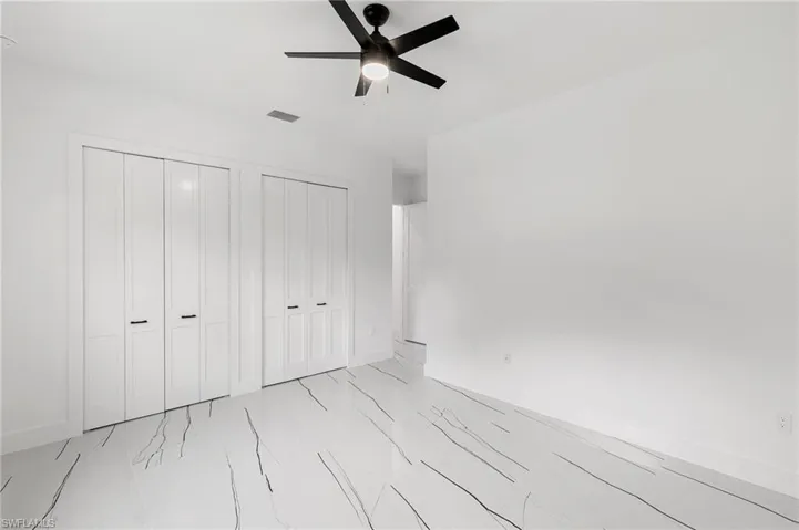 Unfurnished bedroom featuring two closets and ceiling fan