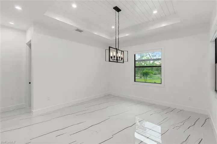 Unfurnished room featuring a notable chandelier, a raised ceiling, and wooden ceiling