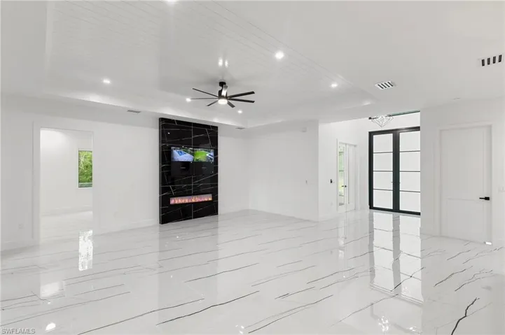 Unfurnished living room featuring a raised ceiling, wood ceiling, a large fireplace, and ceiling fan