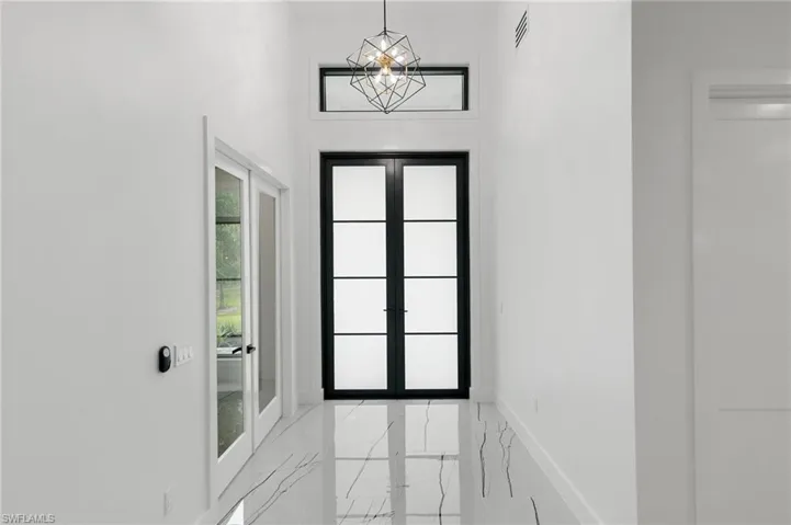 Entryway with an inviting chandelier and french doors