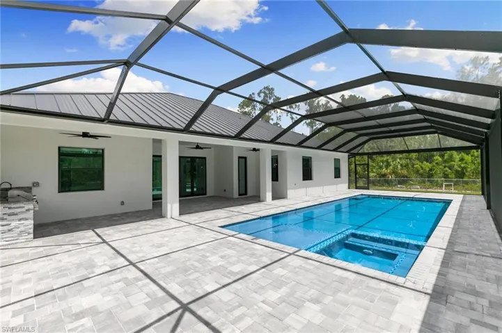 View of swimming pool with ceiling fan, glass enclosure, and a patio area