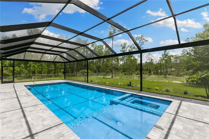 View of swimming pool with a lawn, glass enclosure, and a patio area
