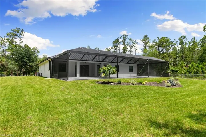 Rear view of house with a lanai and a lawn