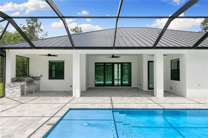 Rear view of property featuring a patio, a lanai, ceiling fan, and exterior kitchen