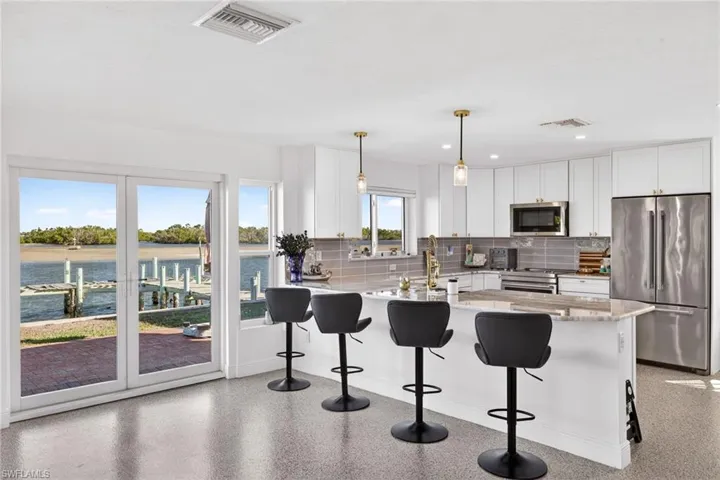 Kitchen featuring high quality appliances, light stone countertops, white cabinetry, a breakfast bar area, and recessed lighting