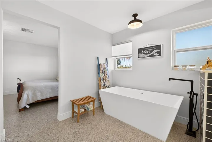 Ensuite bathroom with a freestanding tub and speckle patterned floor