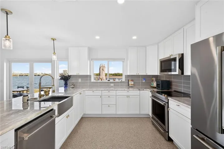 Kitchen featuring appliances with stainless steel finishes, white cabinetry, light stone countertops, and recessed lighting