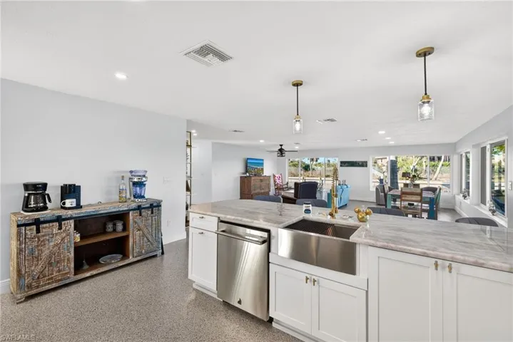 Kitchen with white cabinets, open floor plan, decorative light fixtures, stainless steel dishwasher, and recessed lighting