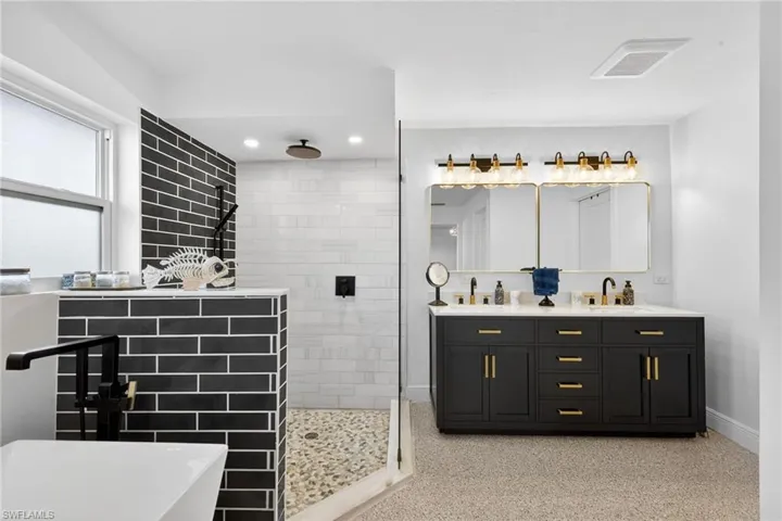 Bathroom featuring a walk in shower, double vanity, and a freestanding bath